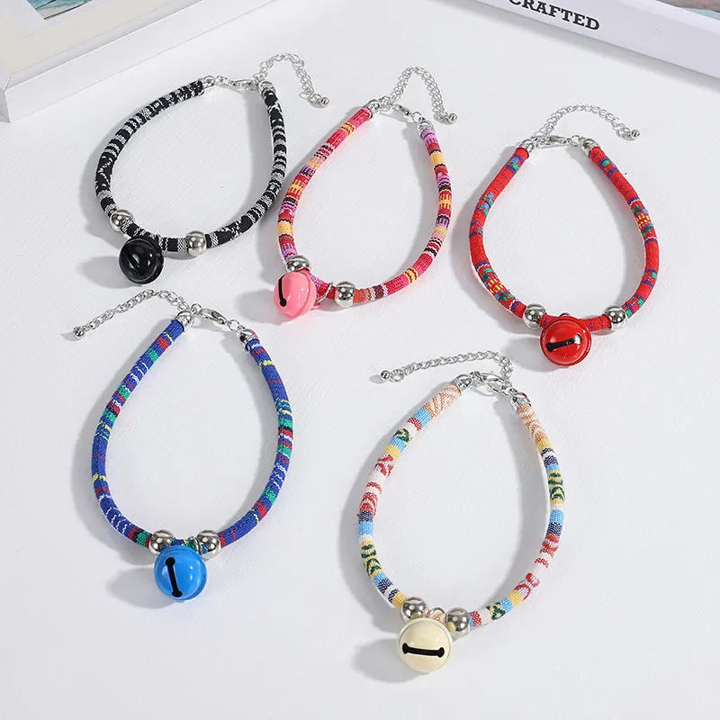 Coloured adjustable nylon pet collar with a metal buckle and brass bell in black, blue, pink, red, and white options.