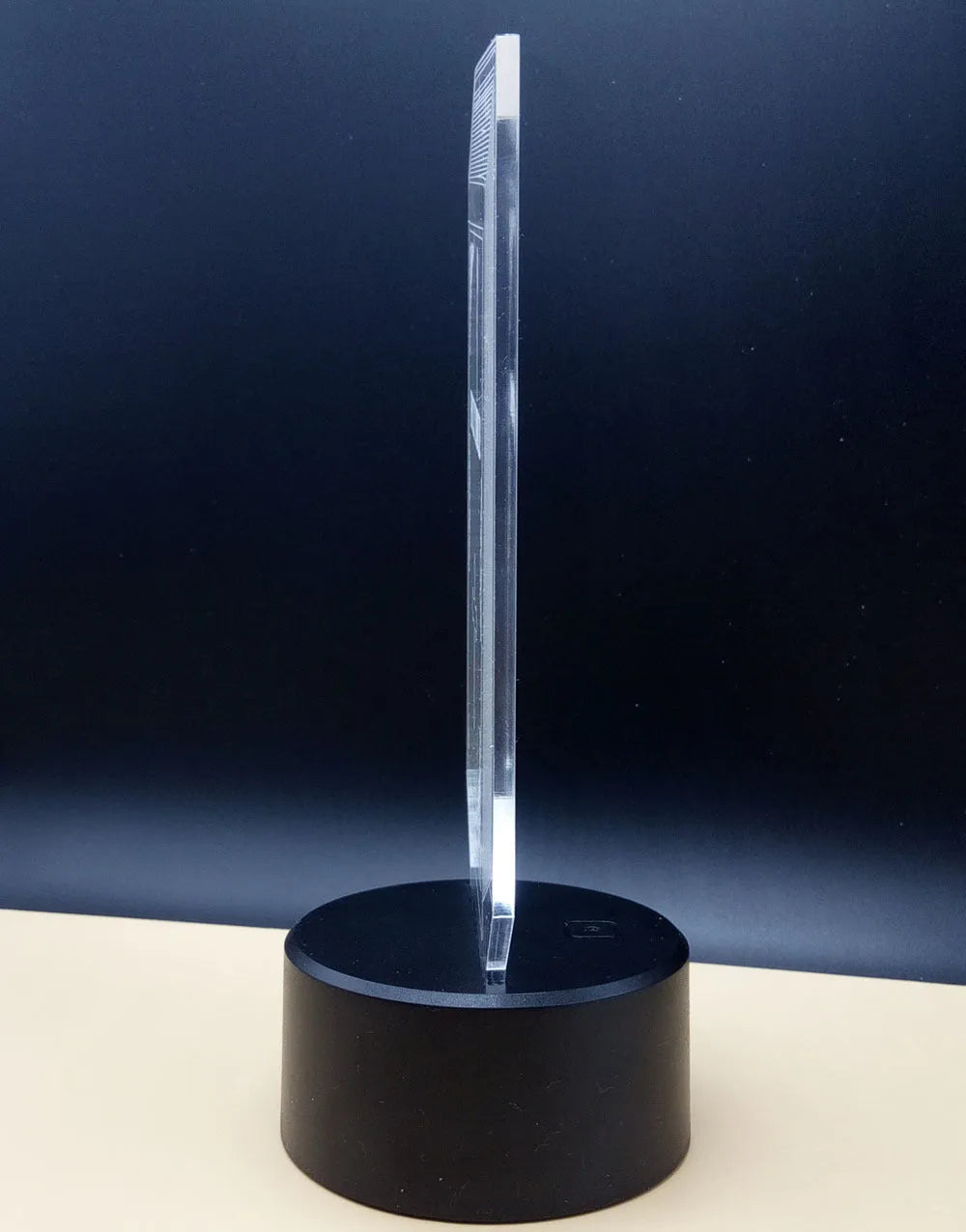 3D acrylic rose flower night light with remote control on a table, displaying purple light.