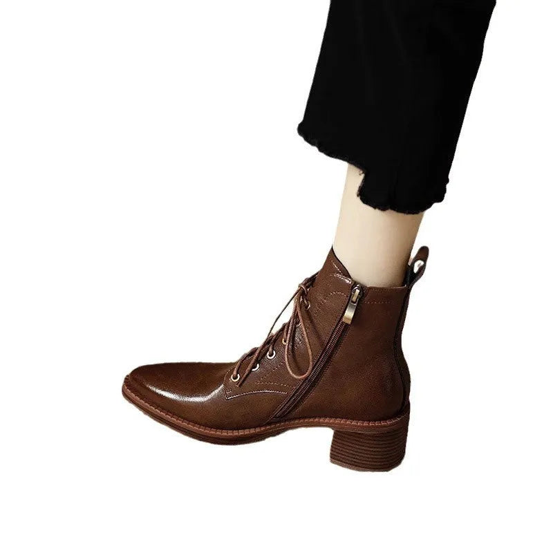 Women's black pointed-toe ankle boots with a low heel on a plain background.