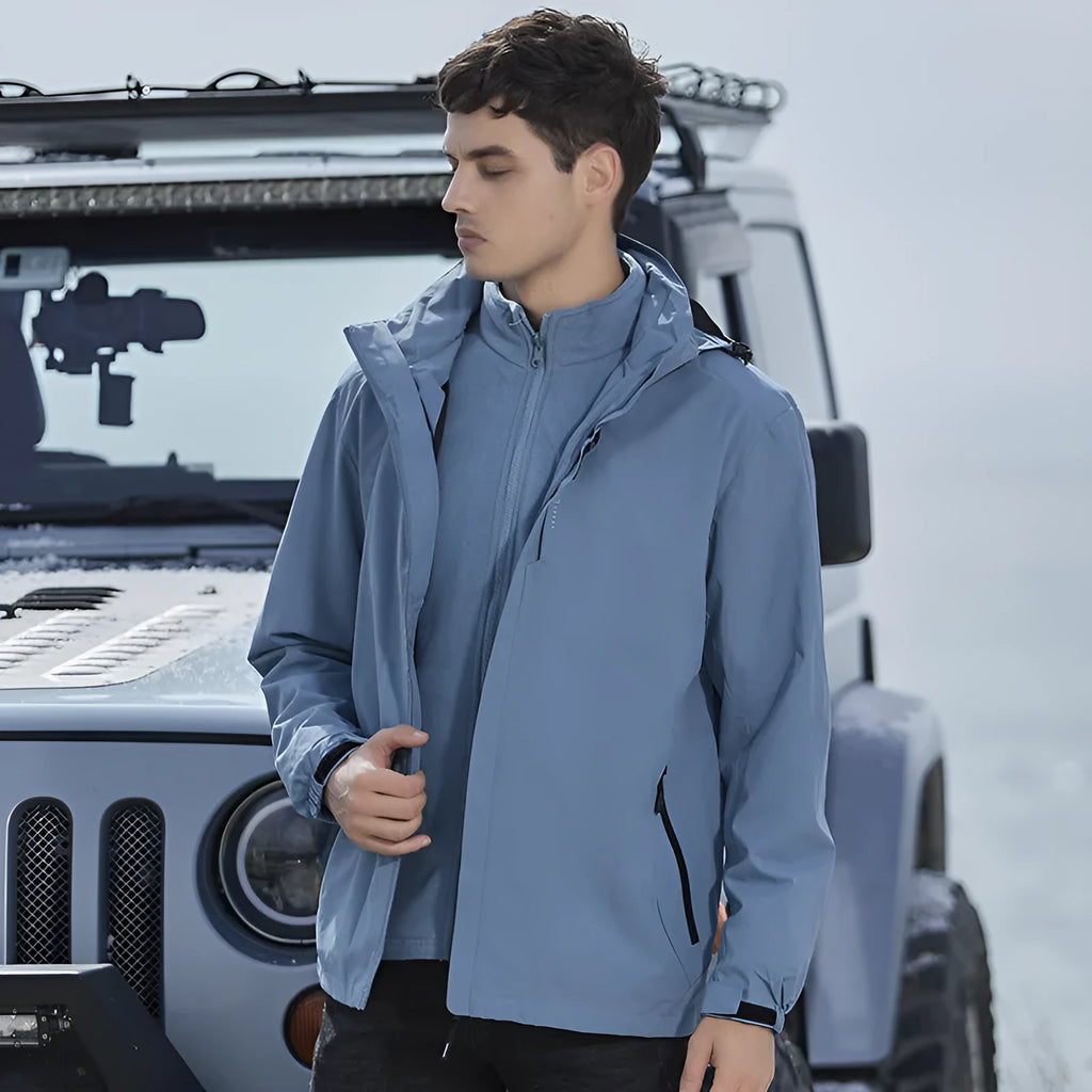 Man modelling a fluorescent orange two-piece waterproof mountaineering suit with a removable fleece lining for outdoor sports.