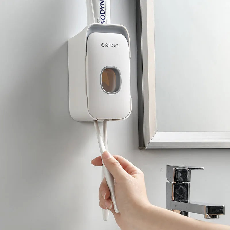 Wall-mounted automatic toothpaste dispenser in blue, grey, and pink colours