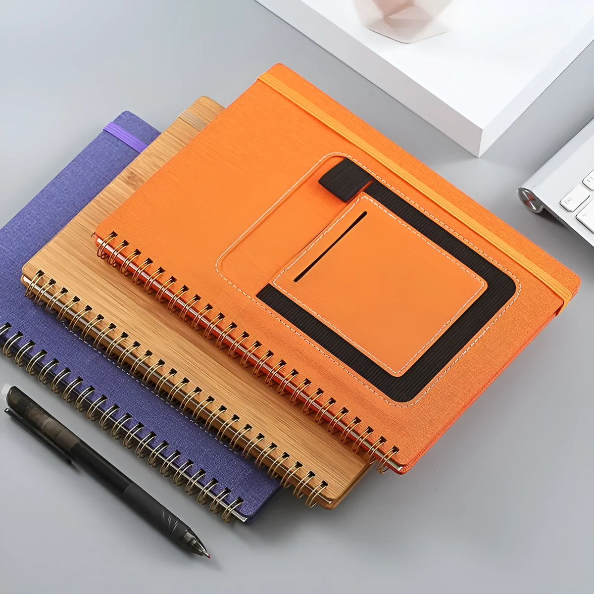 Erasable coil notebook with custom cover on thick waterproof stone paper, shown with pen and cloth.