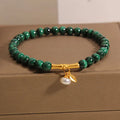 Close-up of a women's white crystal bracelet with a lucky bamboo charm on an elasticated band.