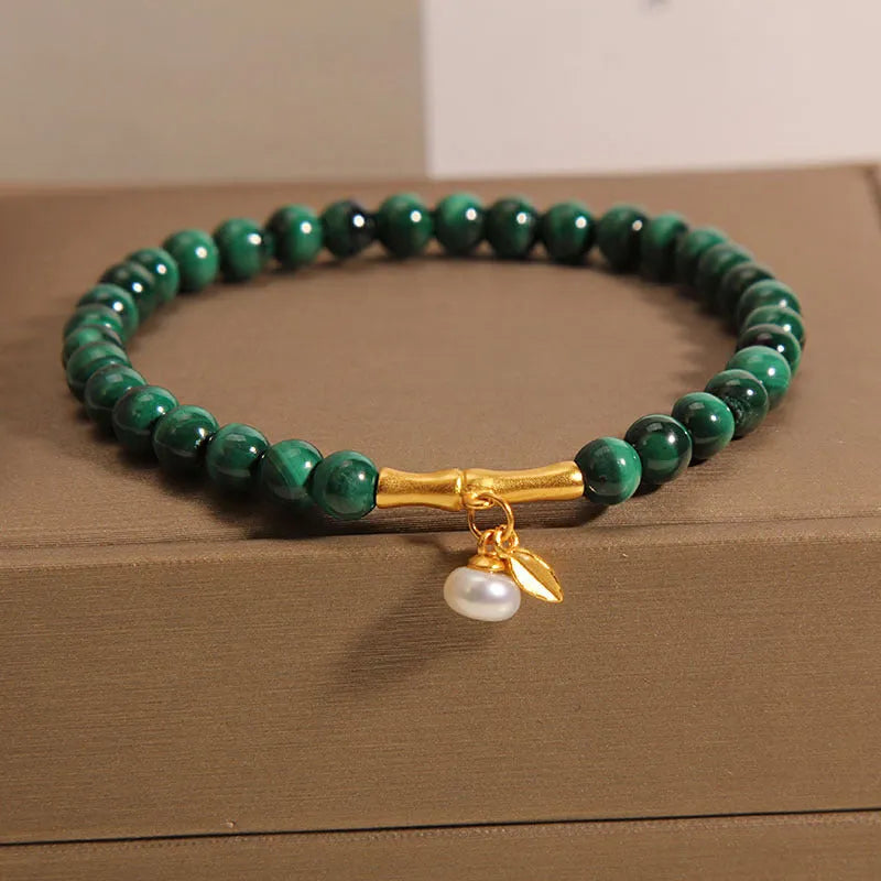 Close-up of a women's white crystal bracelet with a lucky bamboo charm on an elasticated band.