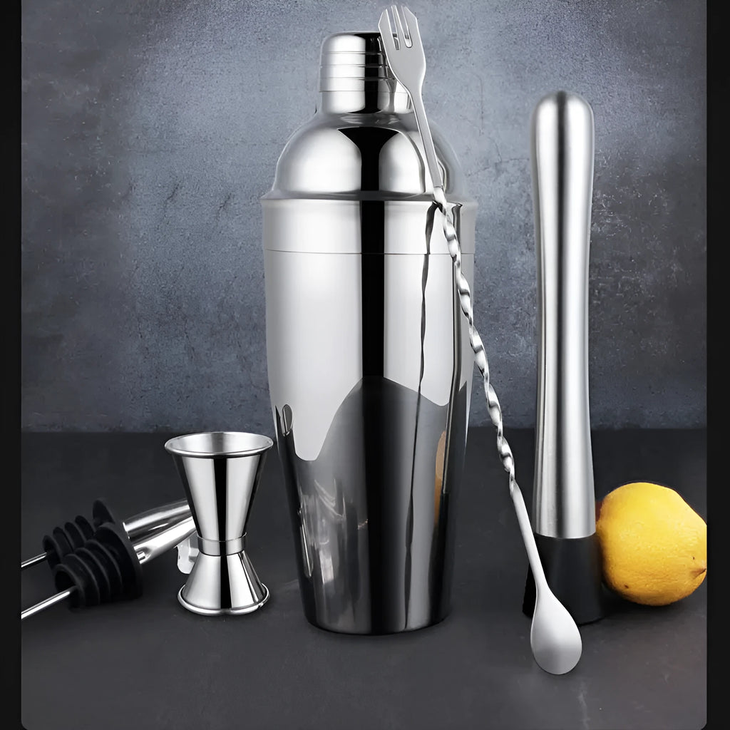 23-piece stainless steel and acrylic cocktail set with shaker, bar spoons, and strainers on a wooden bar.
