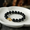 Geometric obsidian black agate and white crystal bracelet with golden dragon bead on adjustable cord.