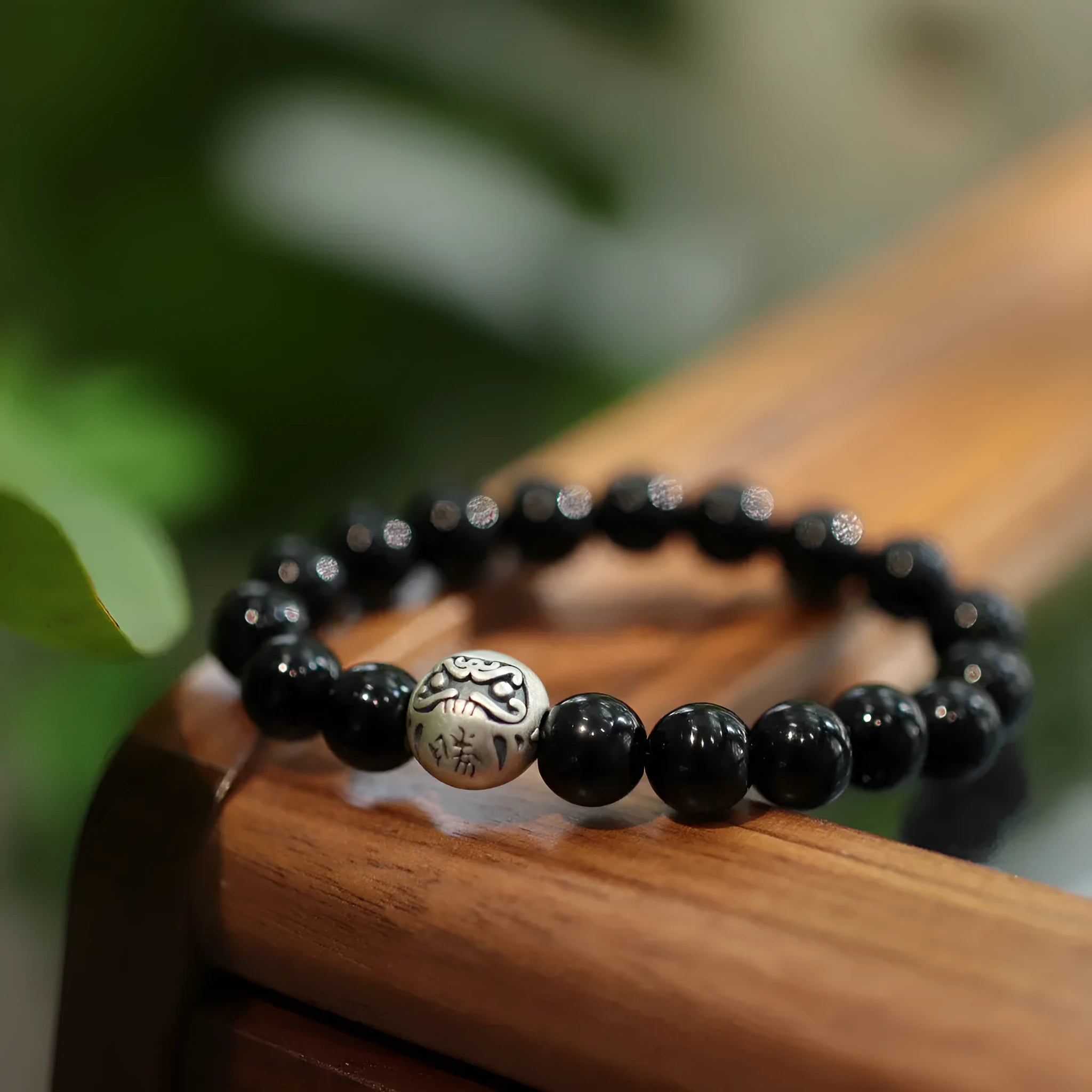 Close-up of a black agate beaded bracelet with a sterling silver clasp on a wrist.