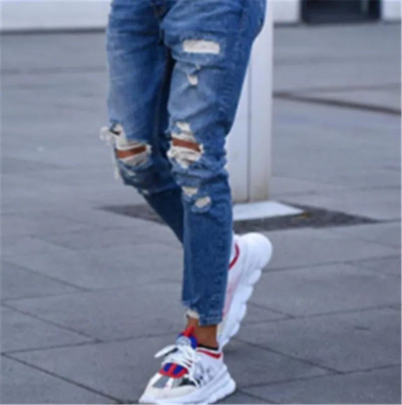 Men's distressed blue jeans with hole detailing on legs, cotton denim fabric