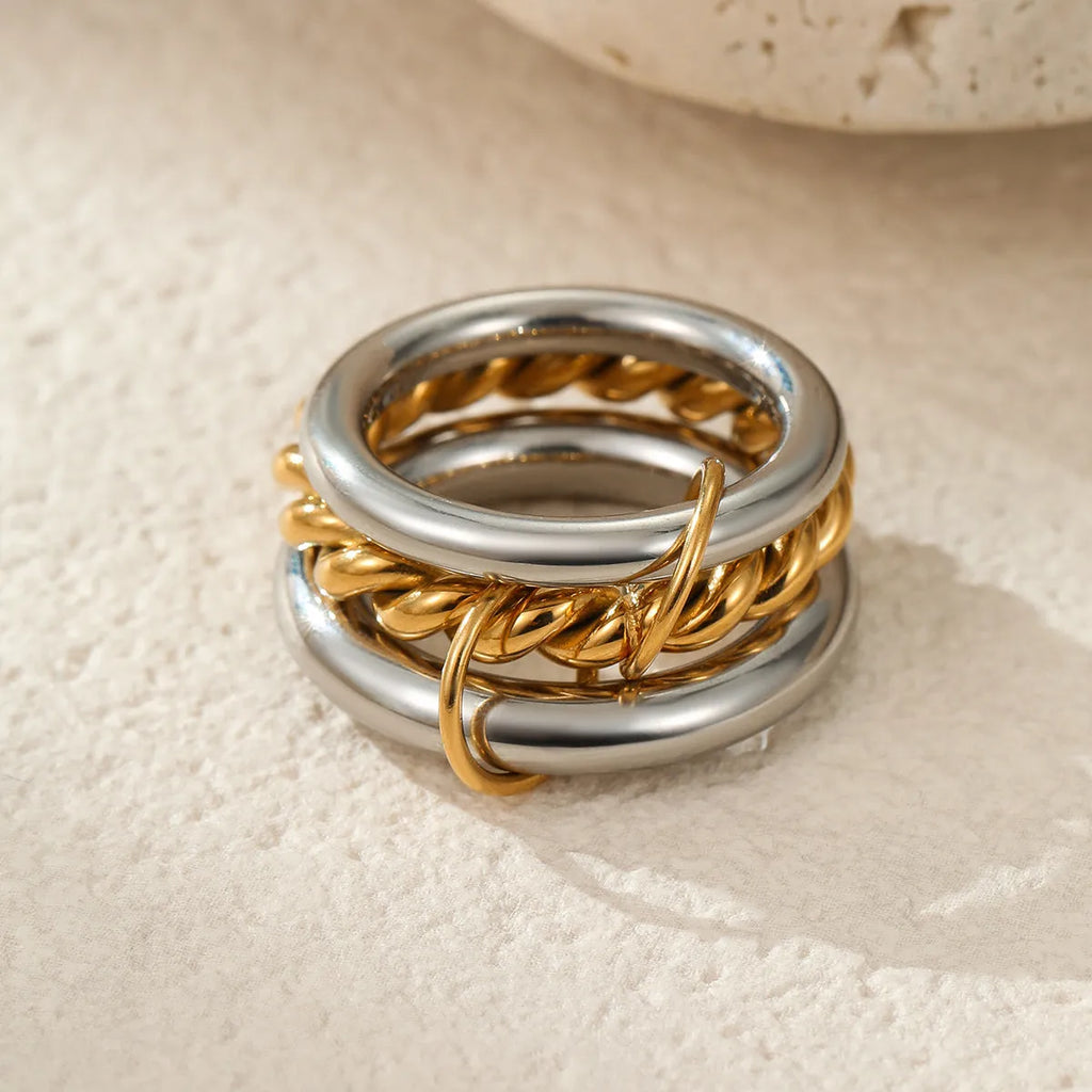 Stacked gold plated stainless steel rings with exaggerated designs on woman's hand