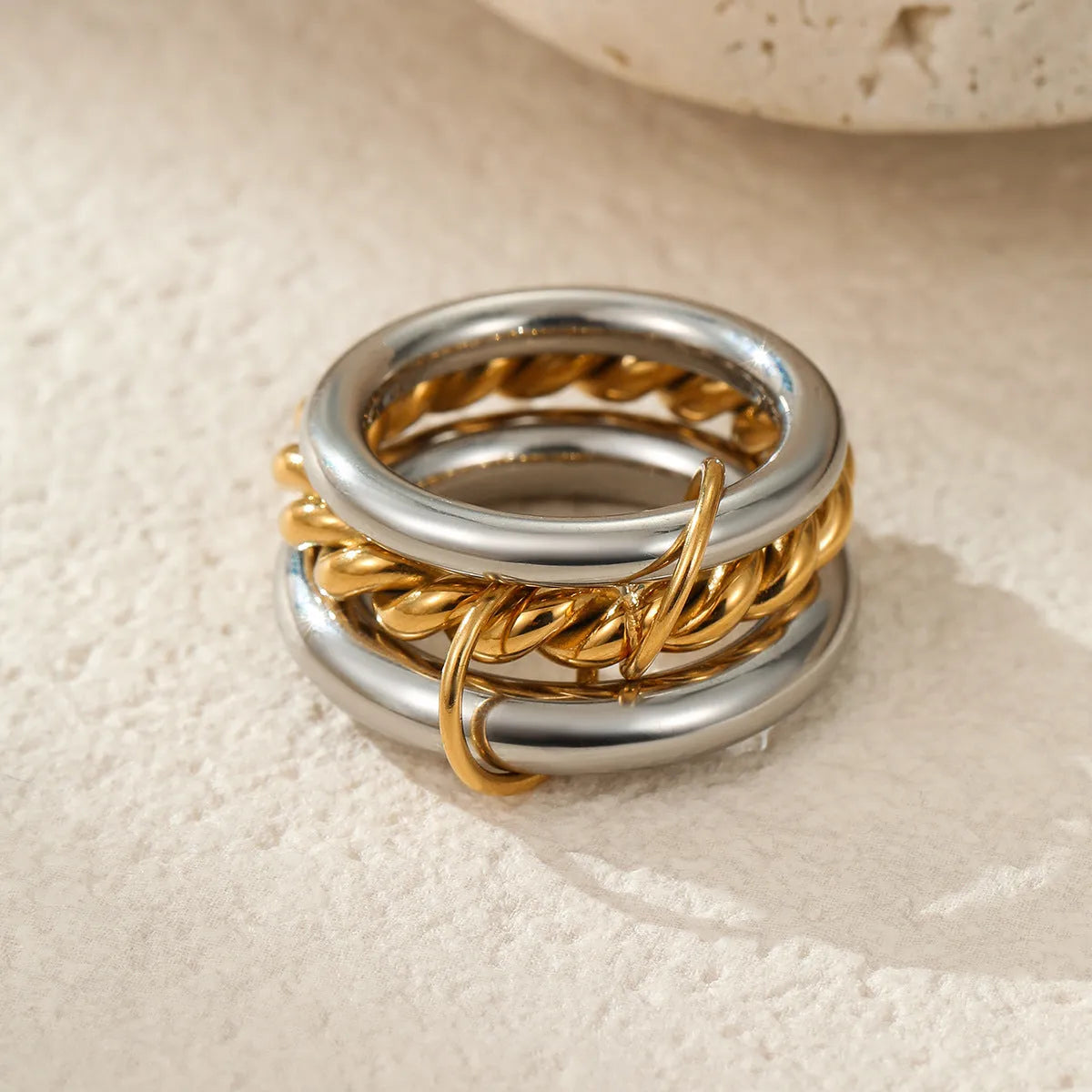 Stacked gold plated stainless steel rings with exaggerated designs on woman's hand