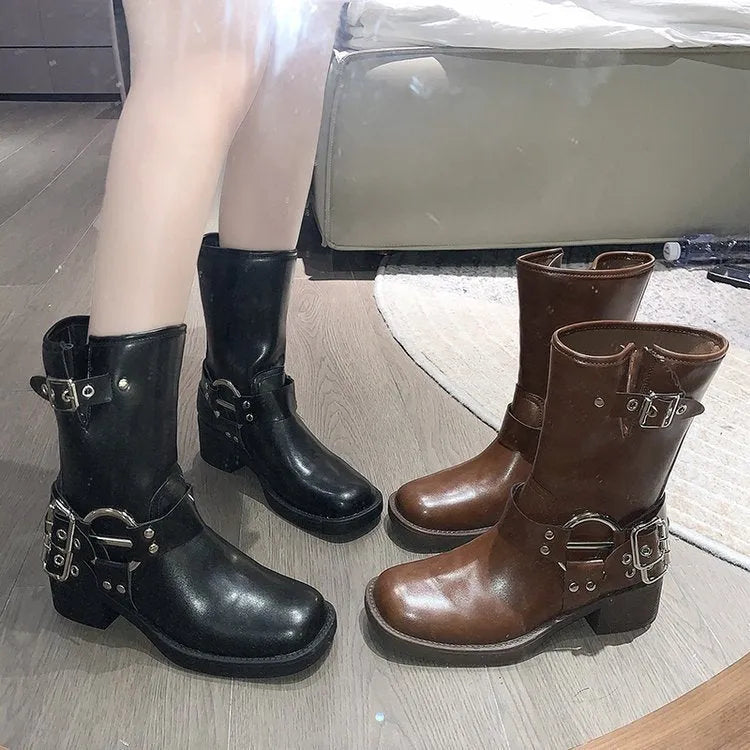 Women's black platform boots with buckle decoration at mid-calf height on a neutral background