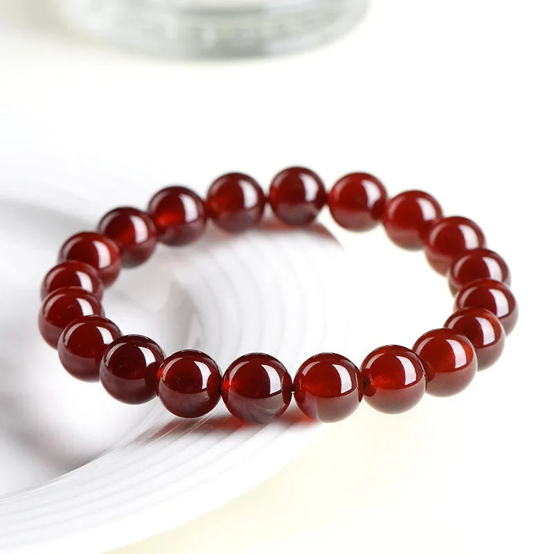 Natural orange red garnet ball bracelet with Ruyi beads on a wrist, showing unisex retro crystal jewellery.
