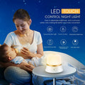 White rechargeable bedside night light with touch controls on a wooden table.