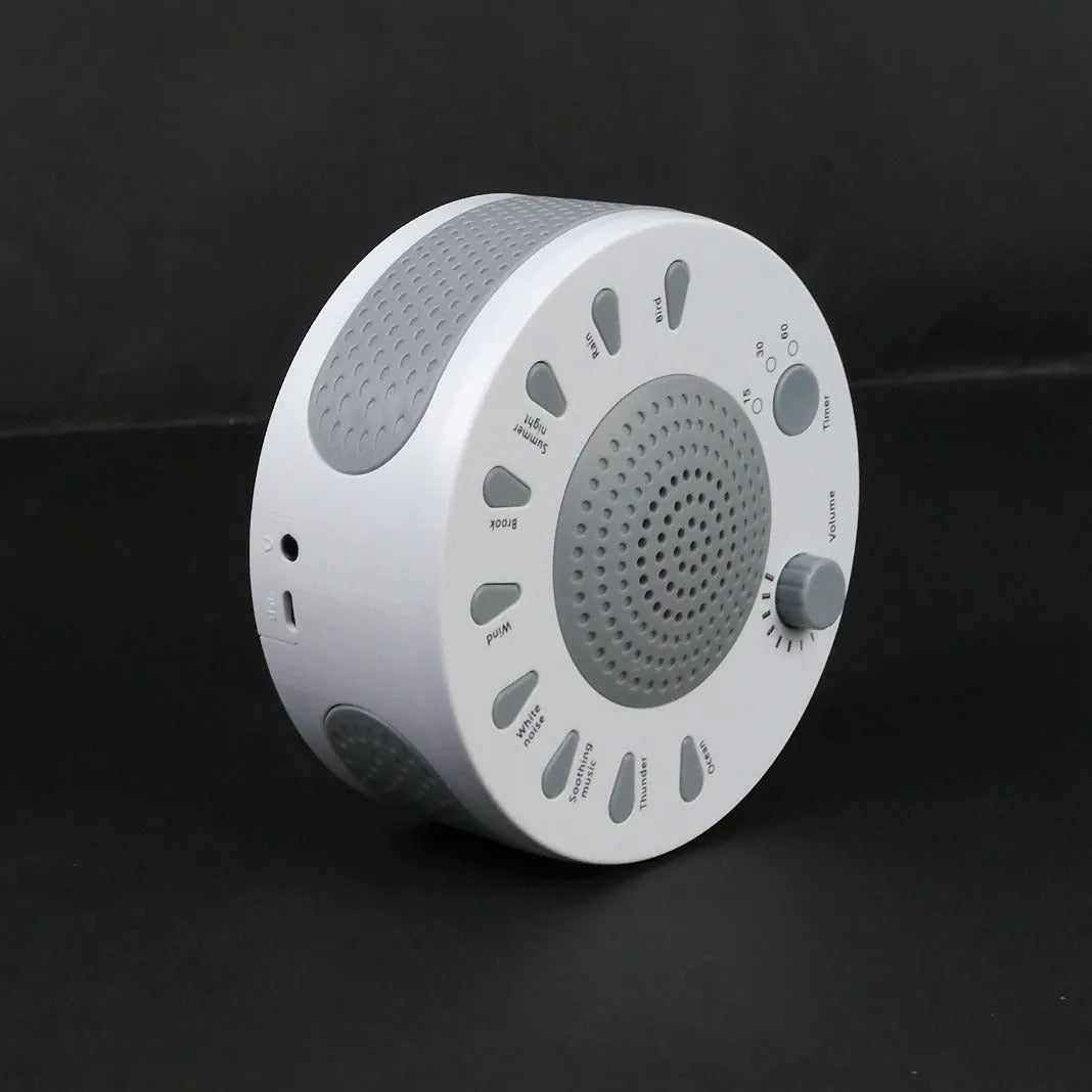 White noise sleep machine with volume knob, showing white colour option, beside USB cable on table