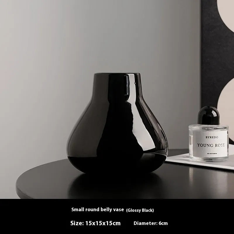 Black ceramic modern vase with white artificial orchid stems on wooden table