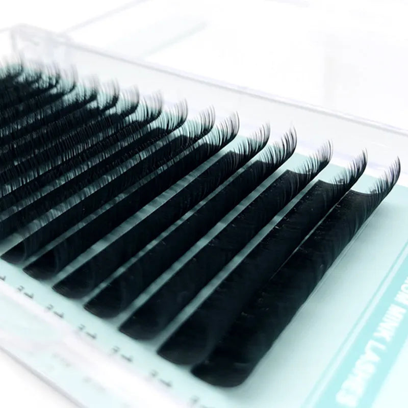 Black artificial fibre false eyelashes showing different length and density options on a clear tray