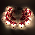 Close-up of warm white Christmas LED string lights with integrated snowman decoration on a green wire garland