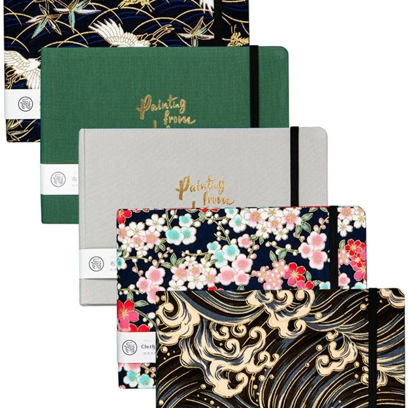 Feiluniao handmade fabric watercolour notebook open on a table with paints, showing a decorative cover.
