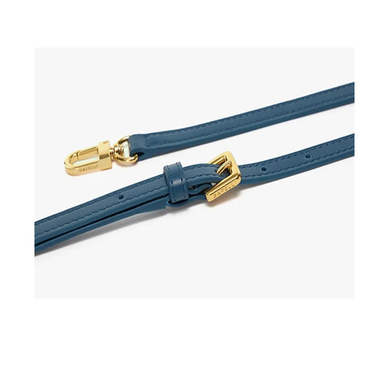 Women's winged leather handbag with cross-body strap in blue, showing latch closure and buckle detail.