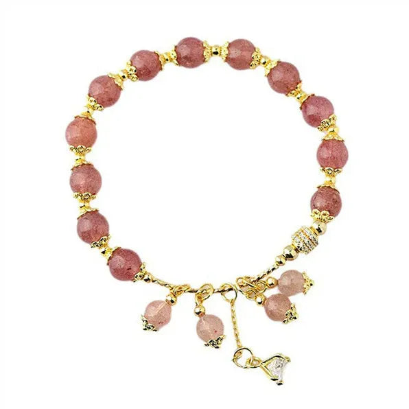 Close-up of a women's pink crystal bracelet with a heart-shaped Strawberry Quartz stone and a white pearl accent.