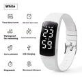 Vibration alarm clock smartwatch with a coloured silicone strap on a wrist, showing its LED display.