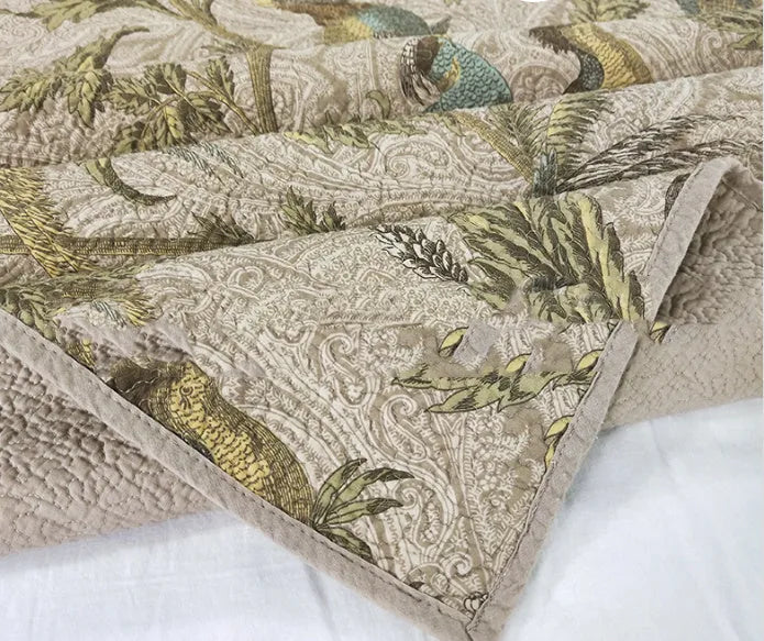 Blue botanical patterned quilted cotton bedspread set on a bed, showing plants, flowers, and bird design.