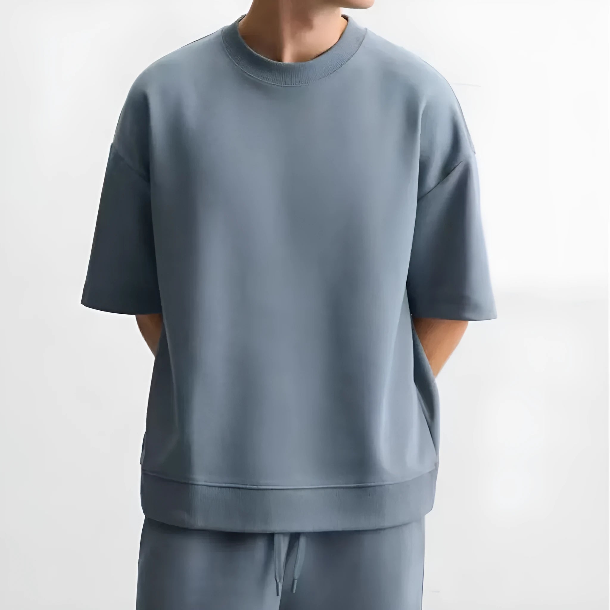 Man wearing a loose blue short sleeve top and matching shorts from a textured polyester casual set.
