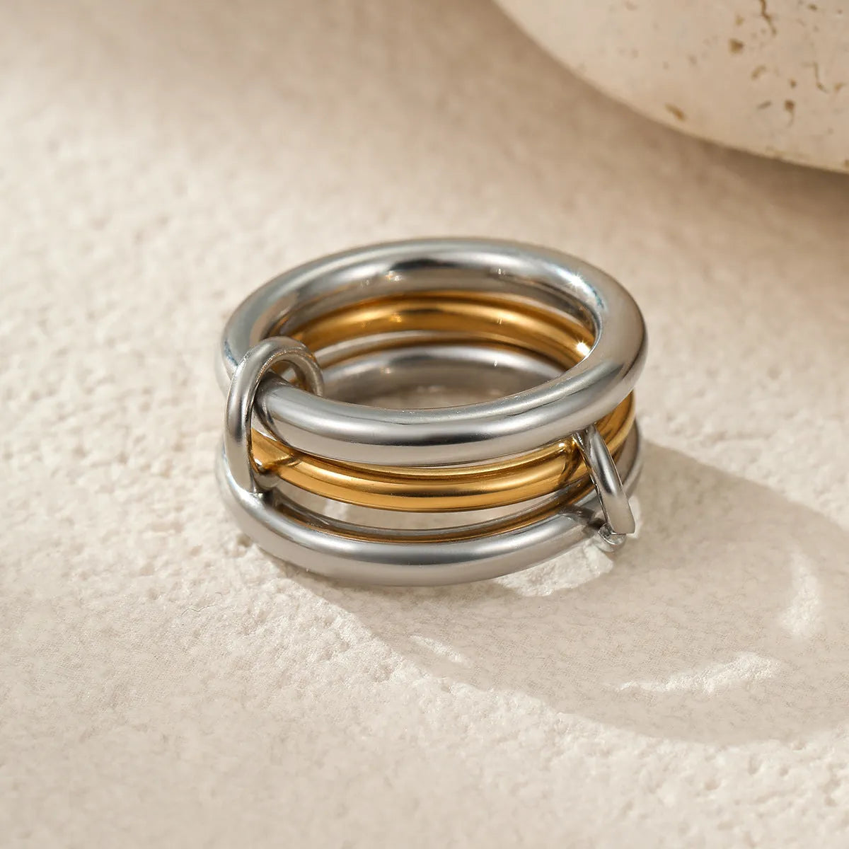 Stacked gold plated stainless steel rings with exaggerated designs on woman's hand