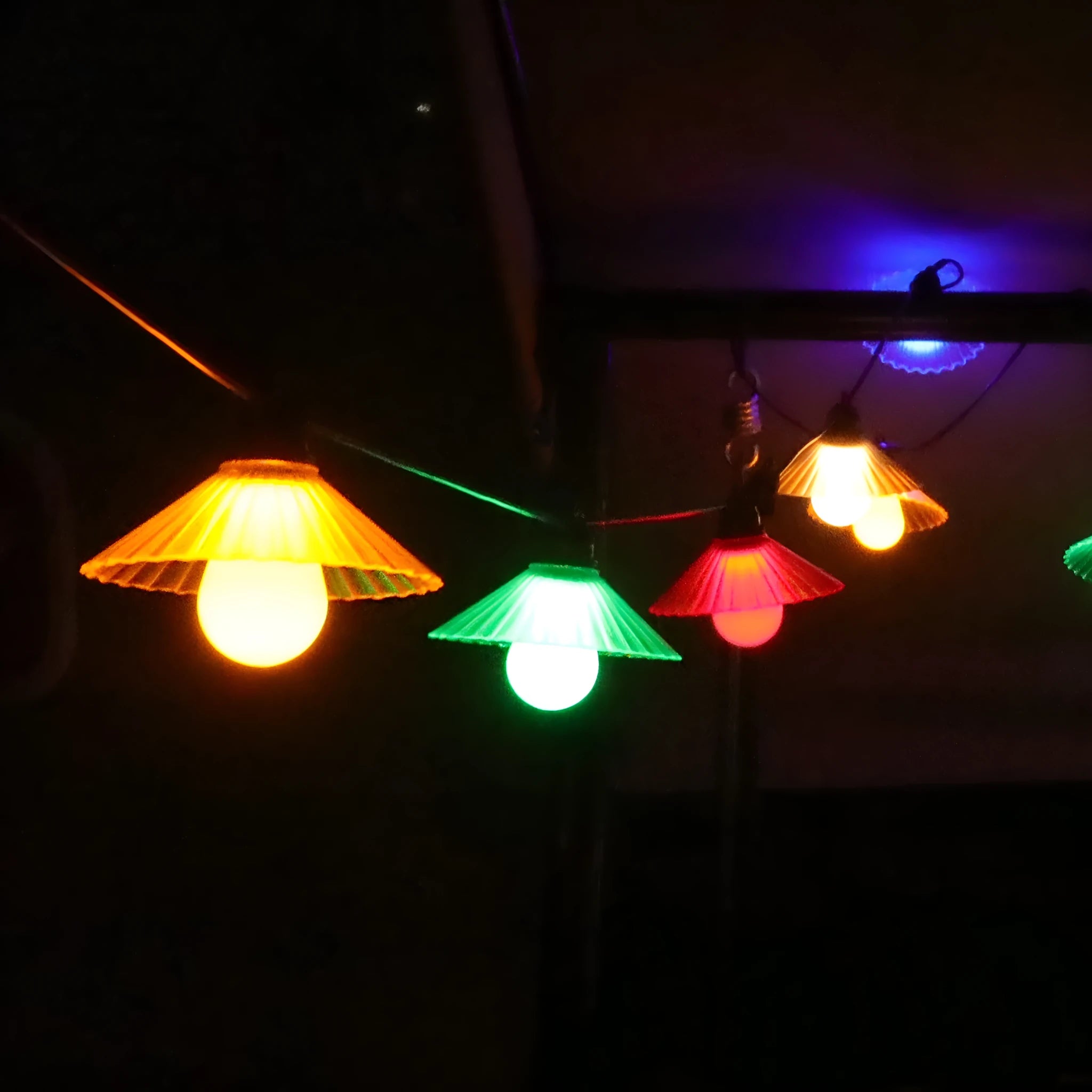 Outdoor LED string lights with flower-shaped white globes hung on a garden fence.