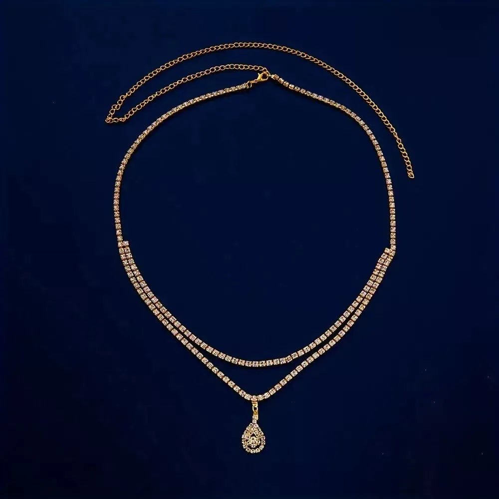 Gold coloured waist chain with a sparkling rhinestone water drop pendant and tassel details.
