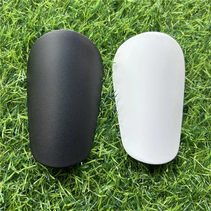 Extra small mini plastic football shin guards for kids in black and white, measuring 8 by 5 centimetres.
