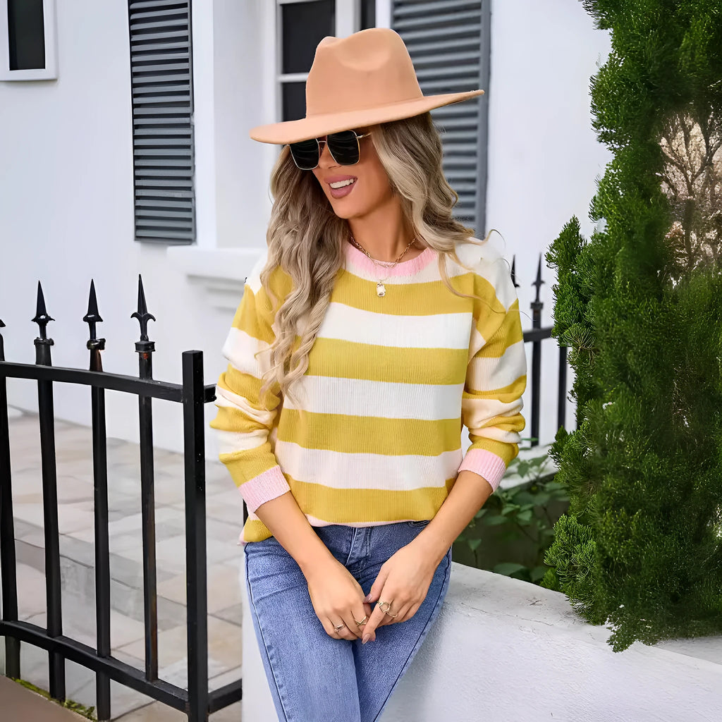 Woman wearing a loose blue and white striped acrylic sweater with long sleeves and a round neck.