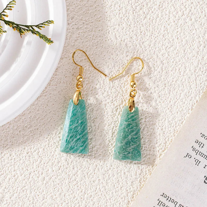 A pair of trapezoid-shaped rough amazonite earrings on a gold and silver background.