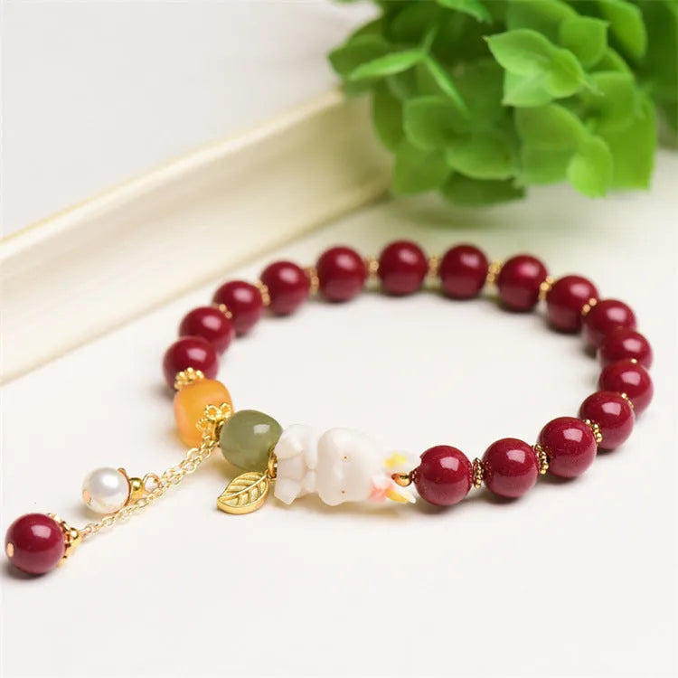 Natural cinnabar bracelet with hand-carved rabbit charm and metallic accents in deep purple-red colour