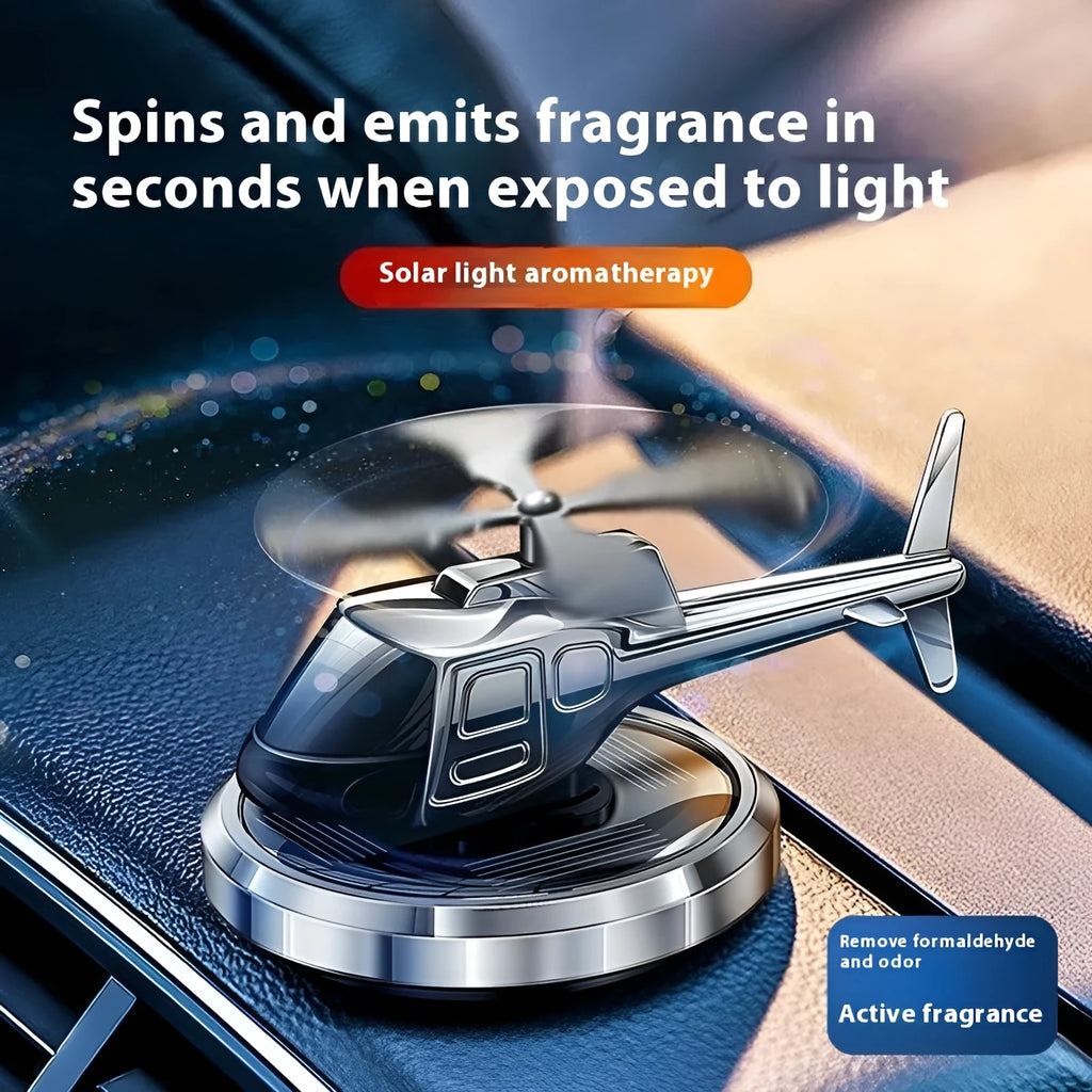 Silver metal solar-powered helicopter car air freshener ornament on a dashboard
