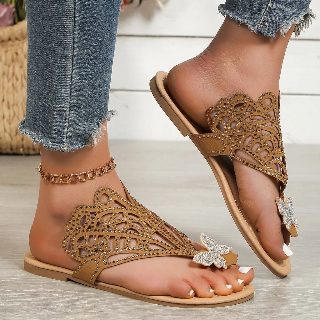 Women's black slip-on sandals with rhinestone decoration and flip-toe design on a white background.