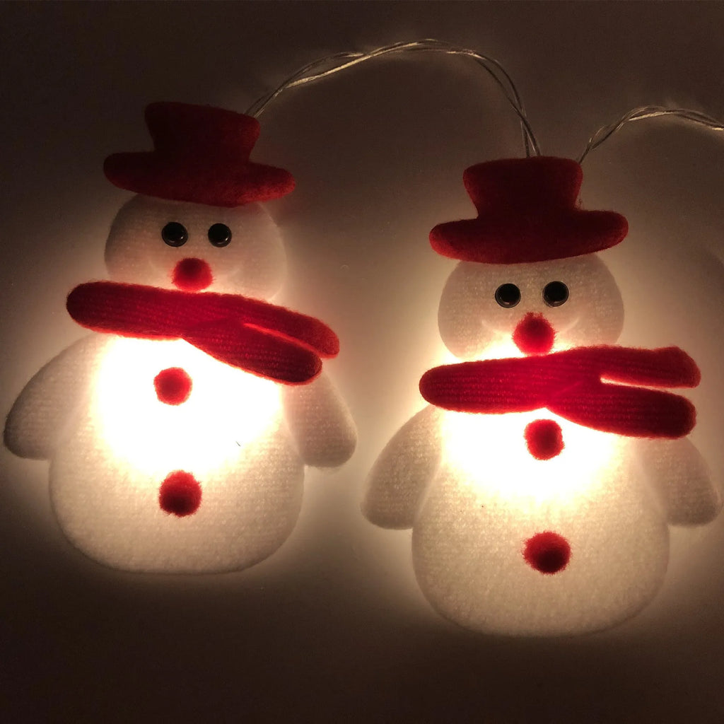 Close-up of warm white Christmas LED string lights with integrated snowman decoration on a green wire garland