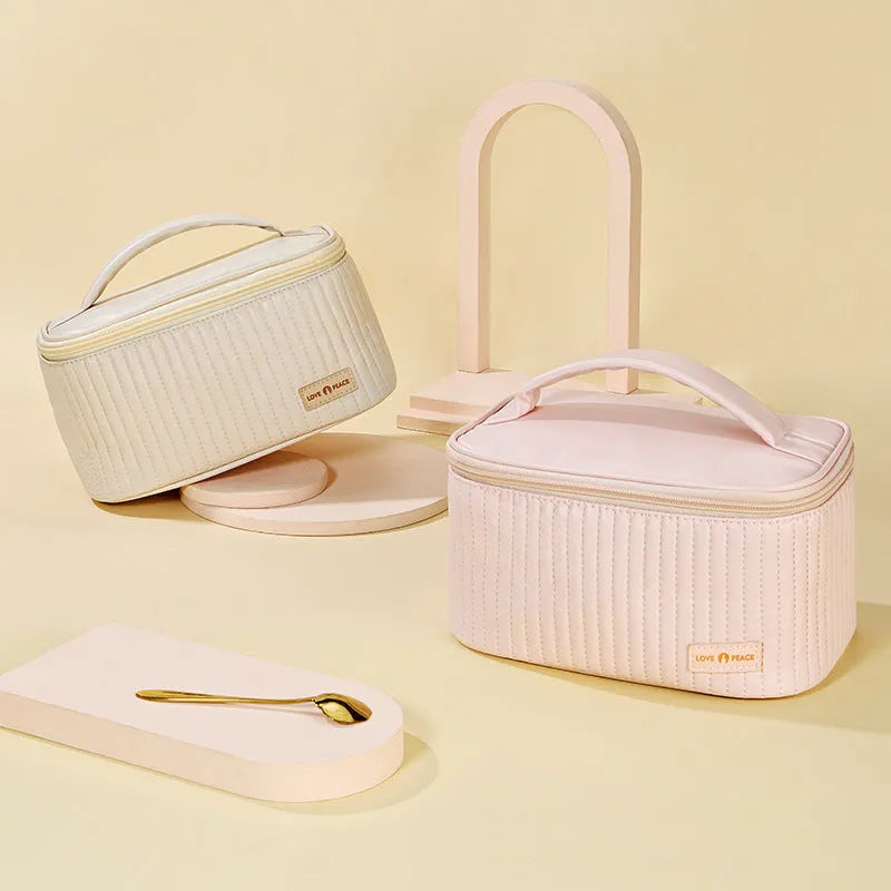 Open-top round pink PU leather makeup bag with a flat bottom on a table.