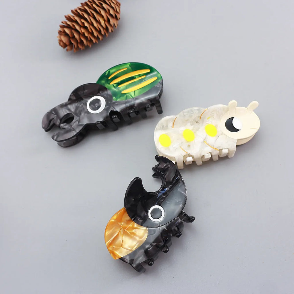 Handmade cartoon beetle grip brooch made from cellulose acetate in green, orange, or white insect designs.