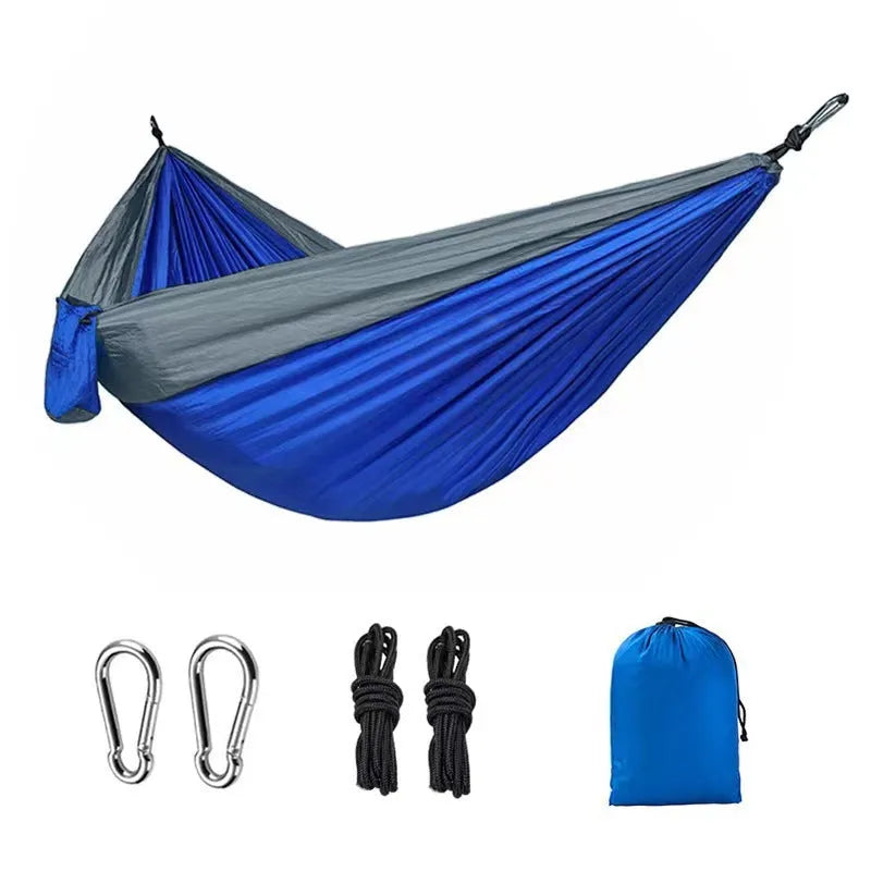 Blue nylon parachute cloth camping hammock hanging between two trees, showing its full 270cm length.
