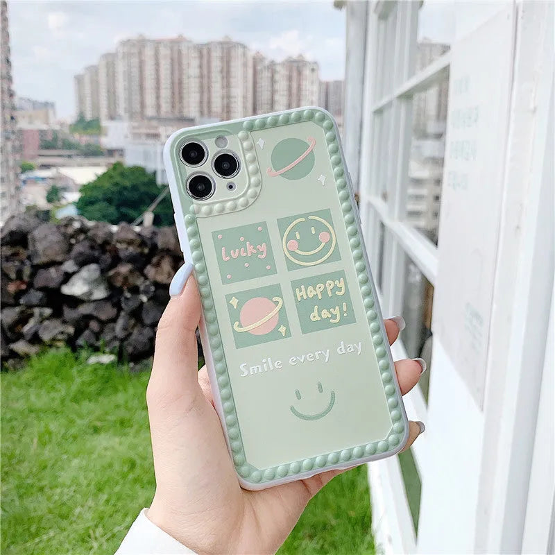Green TPU iPhone case with geometric pattern and smiley face design in a polka dot frame.