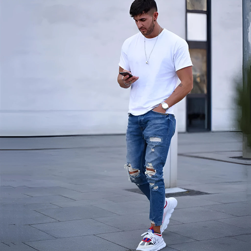 Men's distressed blue jeans with hole detailing on legs, cotton denim fabric