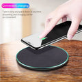 Black Quick Qi wireless charging pad on a desk, compatible with iPhone 11.