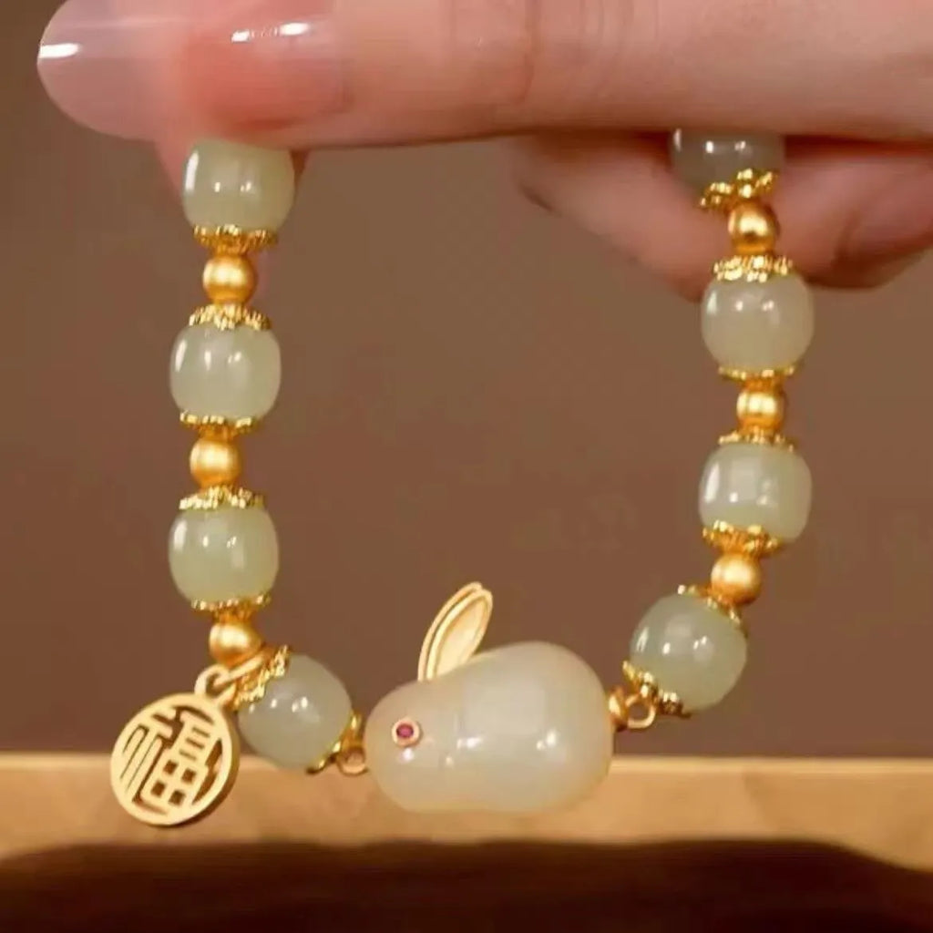 Green fu character and jade hare charm bracelet on black beaded band.