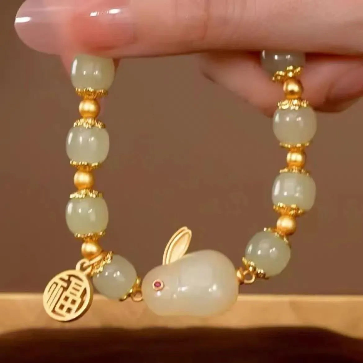 Green fu character and jade hare charm bracelet on black beaded band.
