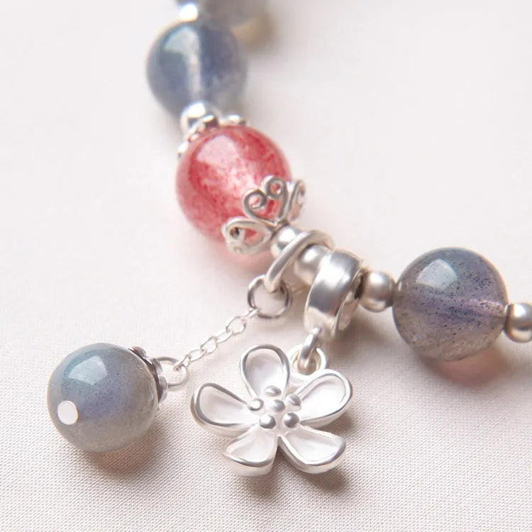 Women's bracelet with pink strawberry quartz and grey moonstone beads on a sterling silver chain with a charm.
