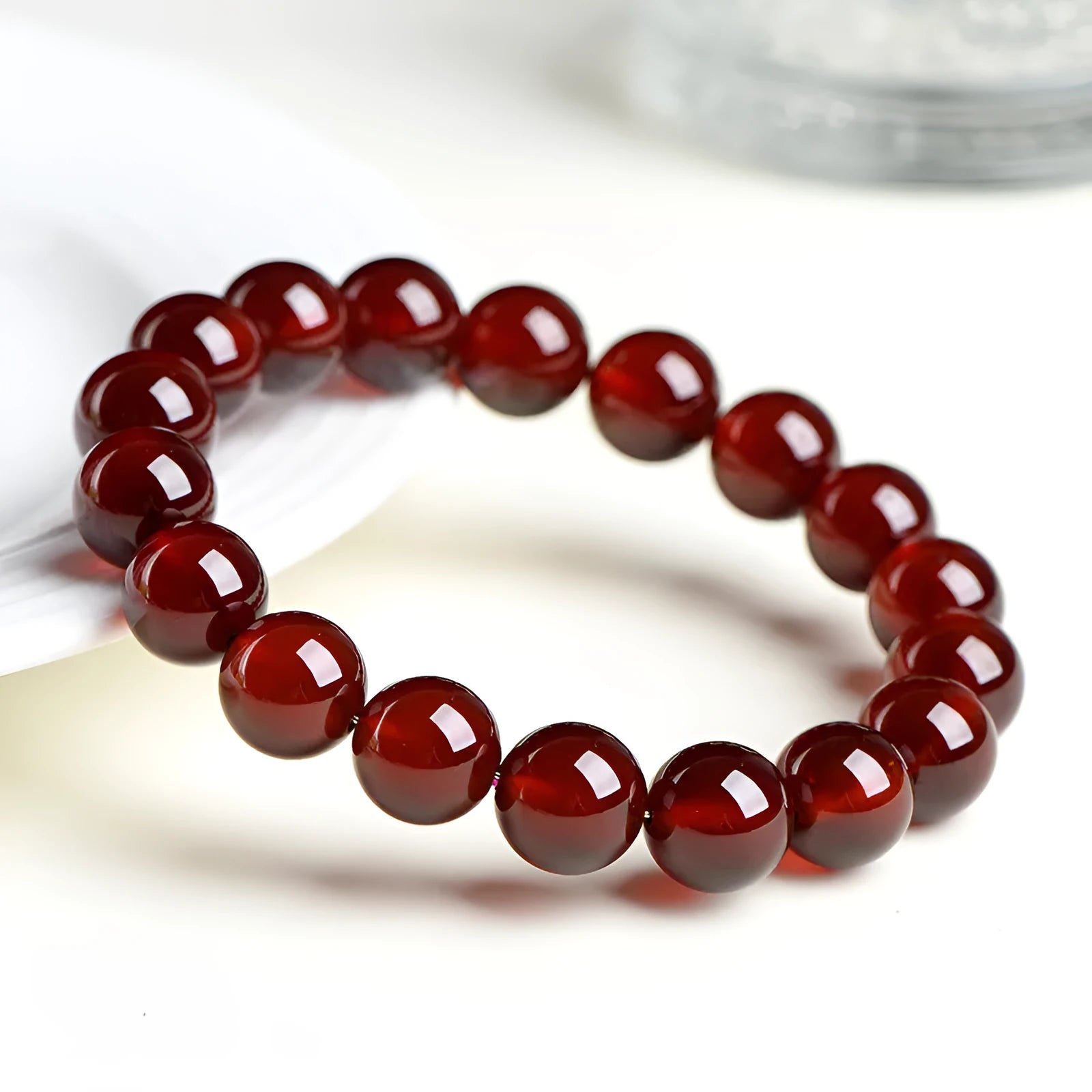 Natural orange red garnet ball bracelet with Ruyi beads on a wrist, showing unisex retro crystal jewellery.