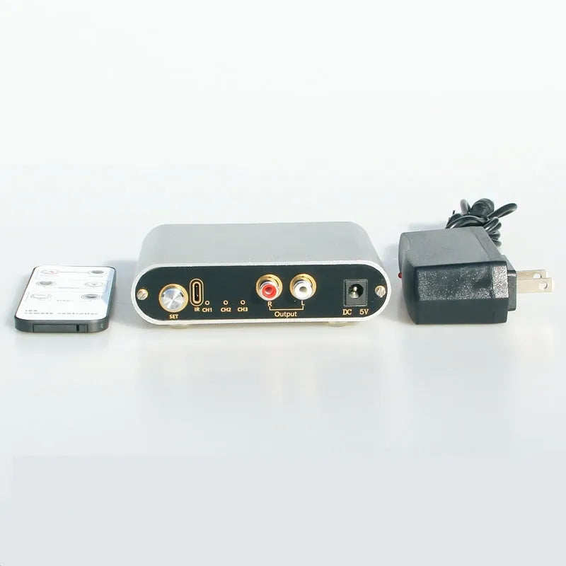 Silver aluminium audio source selector switch box with front button and infrared remote control.