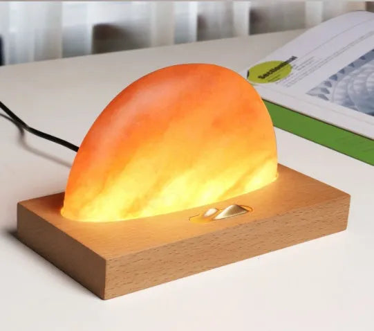 Natural crystal salt lamp with beech wood base featuring integrated wireless phone charging.