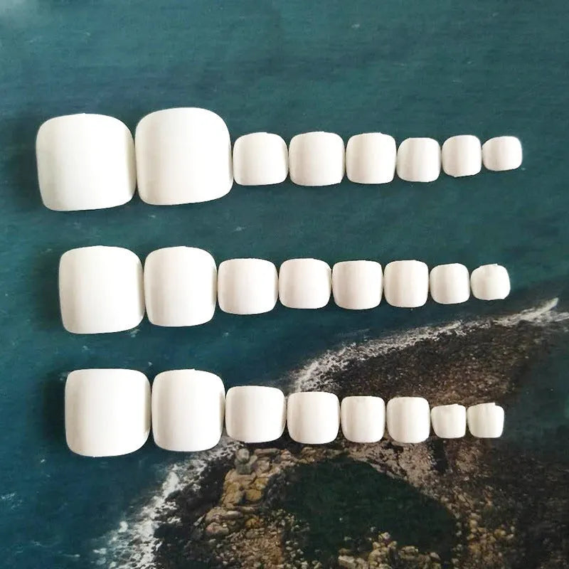 Set of white false nails with a starry sky pattern, shown with adhesive glue.